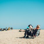 Elderly man with dog enjoying a sunny day at the beach in Barcelona, Spain.