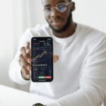 Businessman showing stock graph on smartphone, symbolizing market trends.