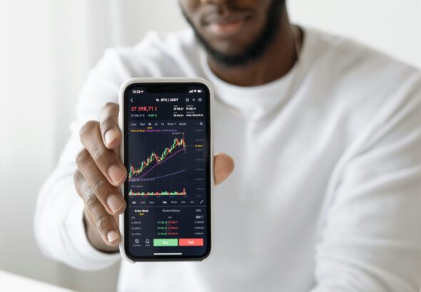 Businessman showing stock graph on smartphone, symbolizing market trends.