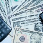 US dollars, calculator, and car keys representing finance and investment tools.